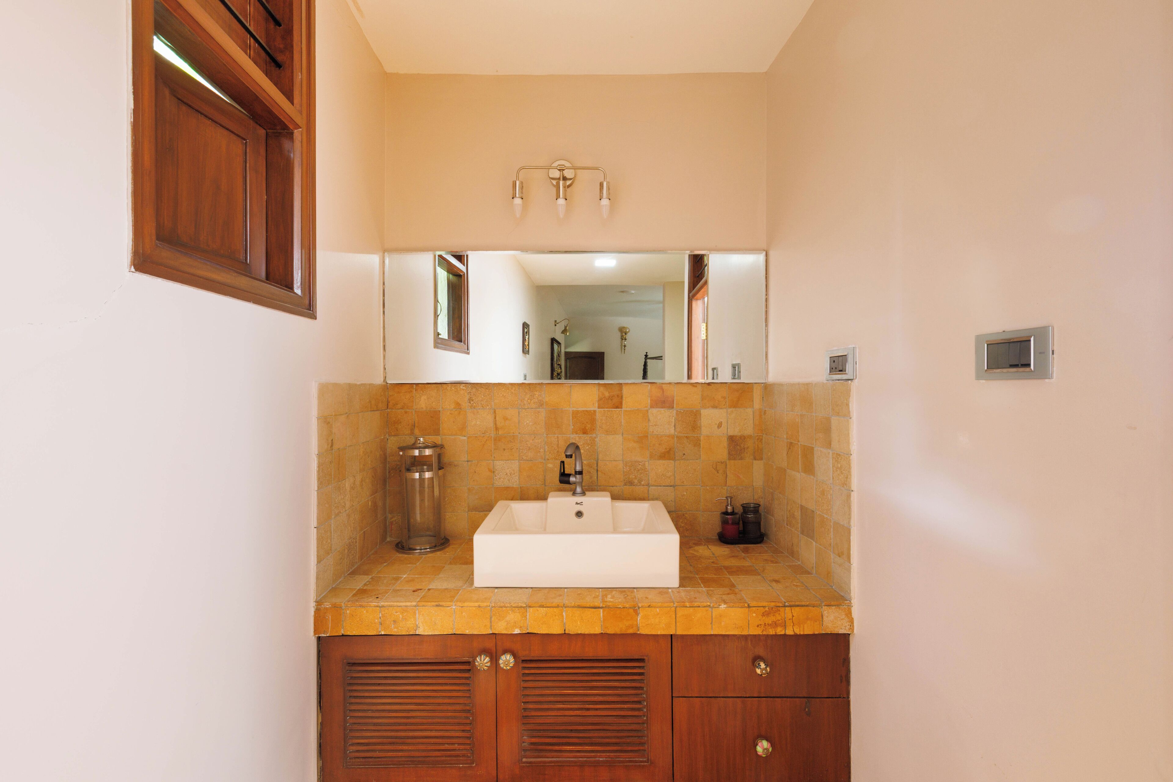 A bathroom with a white sink, wooden cabinets, and a mirror above the sink.