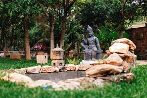 A garden with a statue, rocks, and a small lantern.