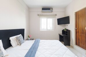 Ein Schlafzimmer mit einem Bett, einem Fernseher, einem Fenster und einer Klimaanlage.