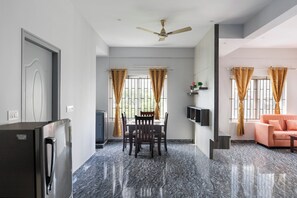 Un espacio habitable moderno con comedor, sofá, televisor y ventilador de techo.