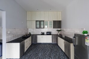 Eine moderne Küche mit schwarzem Marmor-Arbeitsplatz, Holzschränken und einem Edelstahl-Kühlschrank.