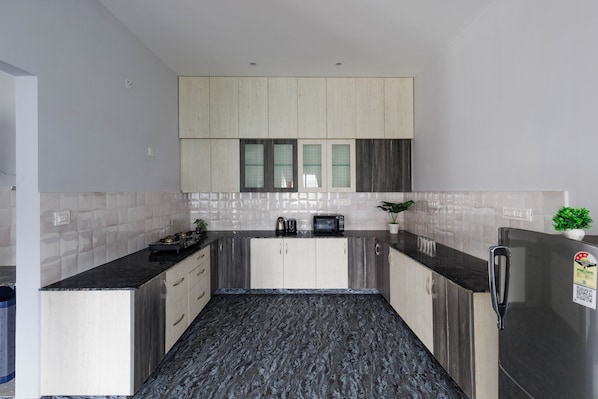 Una cocina moderna con encimera de mármol negro, armarios de madera y refrigerador de acero inoxidable.