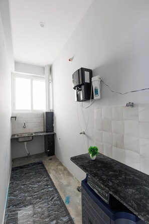 Una cocina con cafetera integrada, un lavamanos y un ventanal.