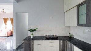 Une cuisine moderne avec des plans de travail sombres, des meubles blancs et un îlot central doté de tiroirs.
