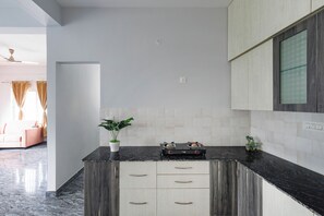 Eine moderne Küche mit dunklen Arbeitsplatten, weißen Schränken und einer zentralen Kochinsel mit Schubladen.