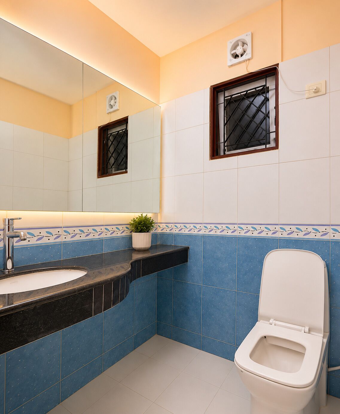 Une salle de bain équipée d’un lavabo, d’un miroir, de toilettes et de carreaux décoratifs.