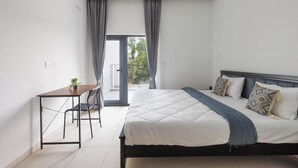 A modern bedroom with a bed, bedside table, and a small desk with a chair. - Orionrosewood Villa by Redolive3bhkacnr Airport (Bengaluru)