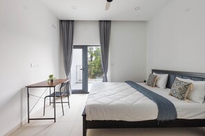 A modern bedroom with a bed, bedside table, and a small desk with a chair. - Orionrosewood Villa by Redolive3bhkacnr Airport (Bengaluru)