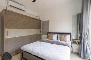 A modern bedroom with a large bed, a built-in wardrobe, and a bedside table with a mirror. - Orionrosewood Villa by Redolive3bhkacnr Airport (Bengaluru)