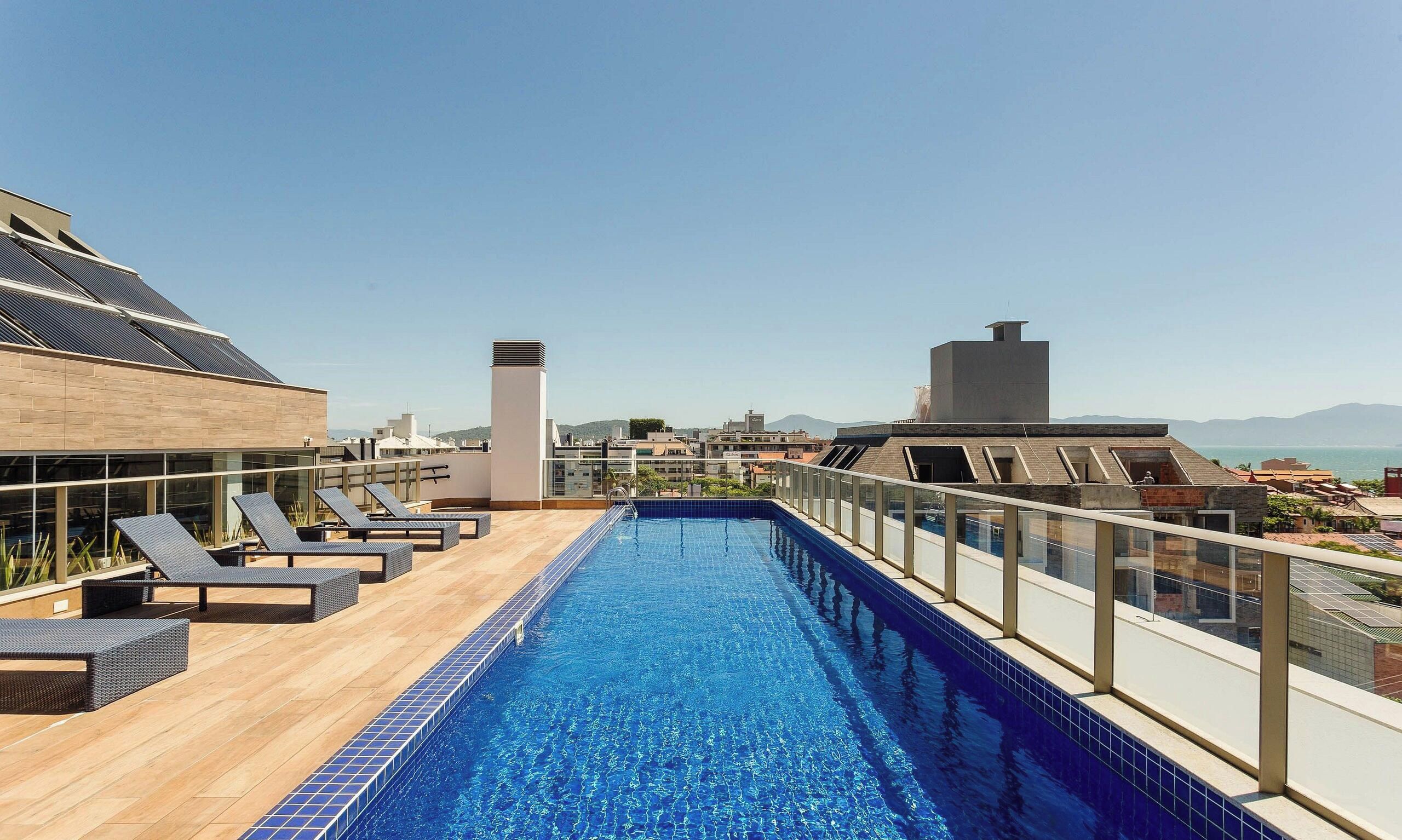 A rooftop pool with lounge chairs and a view of the cityscape.