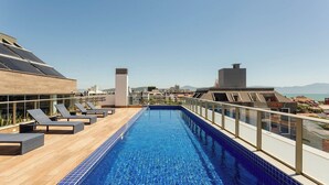 A rooftop pool with lounge chairs and a view of the cityscape. - Apt w/ Rooftop and Pool 300m From Beach Elu0211 (Florianópolis)