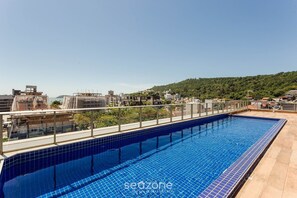 En pool på taket med fri utsikt över de omgivande byggnaderna och en kulle i bakgrunden.