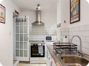 A compact kitchen with a built-in oven, microwave, and stainless steel sink. - Private, Spacious, Excellent Transport Links Farringdon & St Pancras London (London)