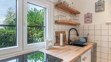 Eine moderne Küche mit einem großen Fenster, Holzregalen und einem schwarzen Wasserhahn.