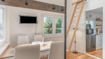 A modern kitchen with a built-in microwave, a wooden ladder, and a view of the outdoors through large windows.