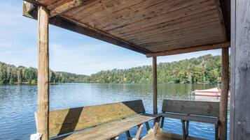 Eine Holzsteganlage mit einer Bank, mit Blick auf einen ruhigen See, dessen Hintergrund ein bewaldeter Hang ist.