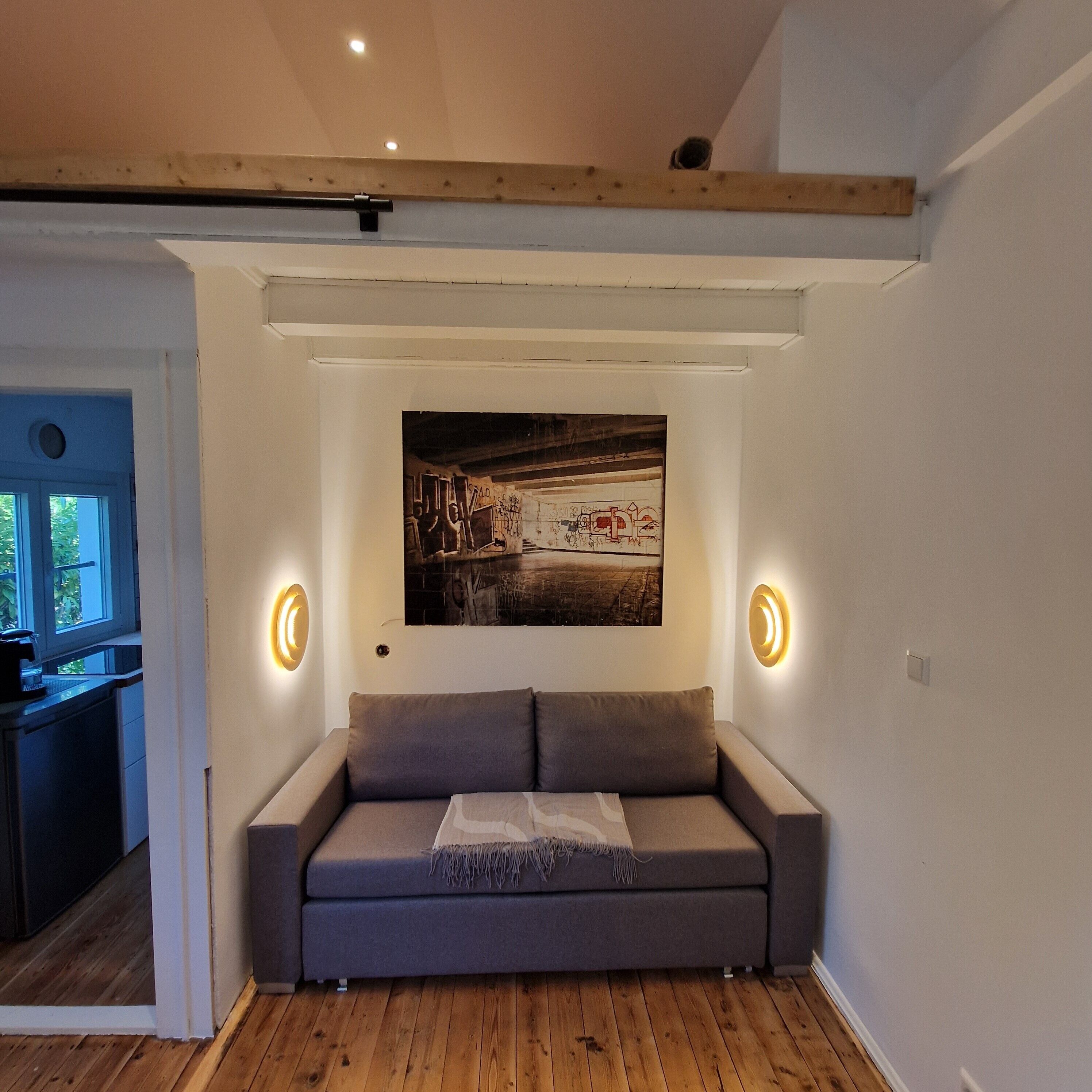 Ein Zimmer mit einer Couch, einem Gemälde und zwei Wandleuchten.