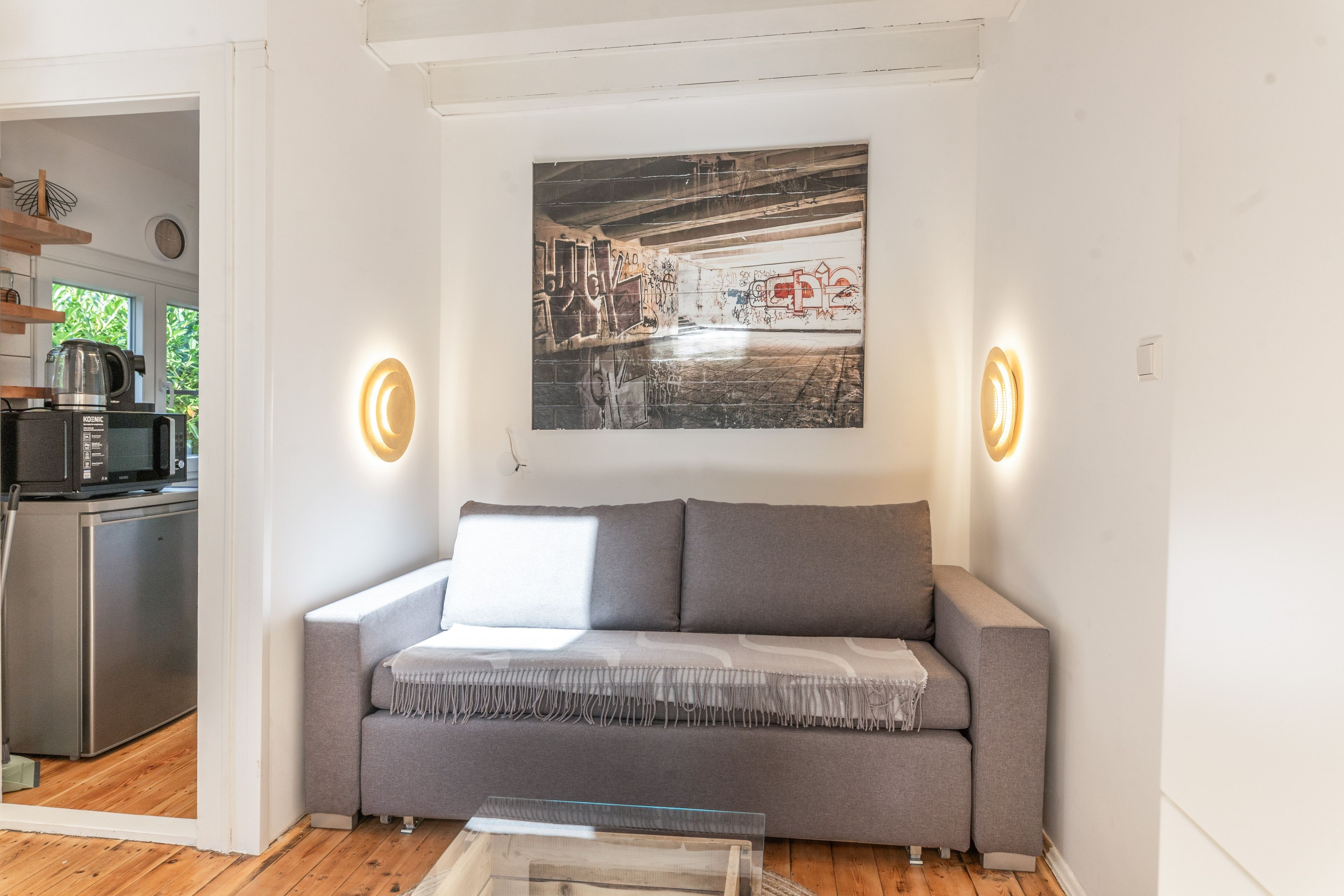 Ein modernes Wohnzimmer mit einem grauen Sofa, einem Couchtisch und einem Wandbild.