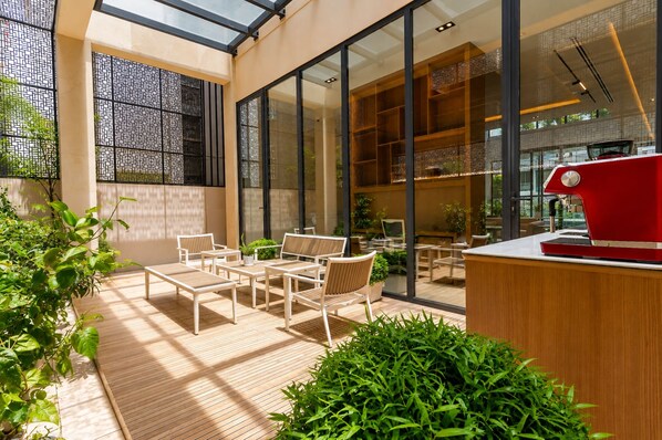 A modern indoor space with a glass ceiling, wooden flooring, and a red coffee machine on a counter.