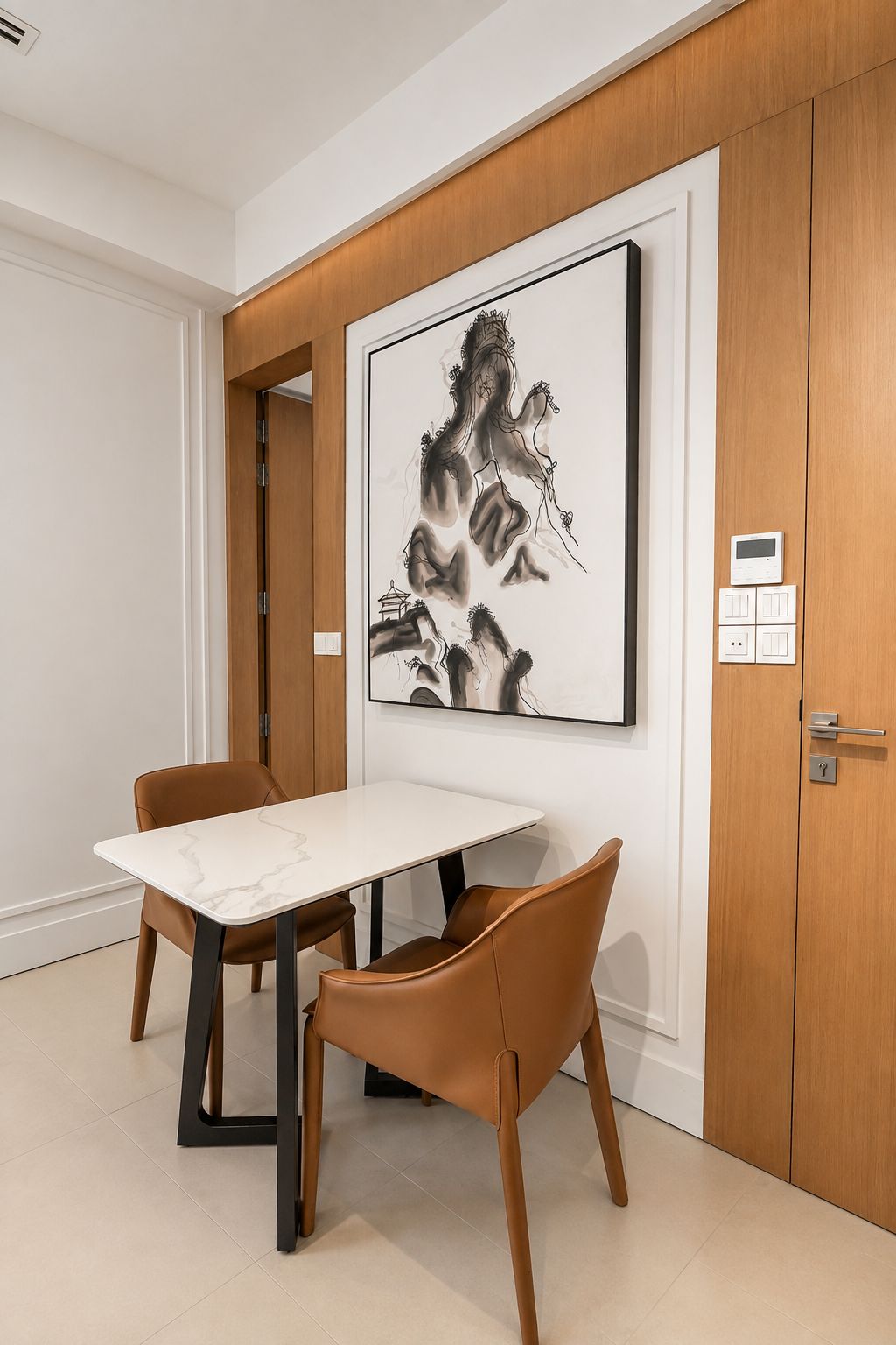 A room with a white marble table, brown leather chairs, a framed artwork on the wall, and a wooden door with a digital thermostat.