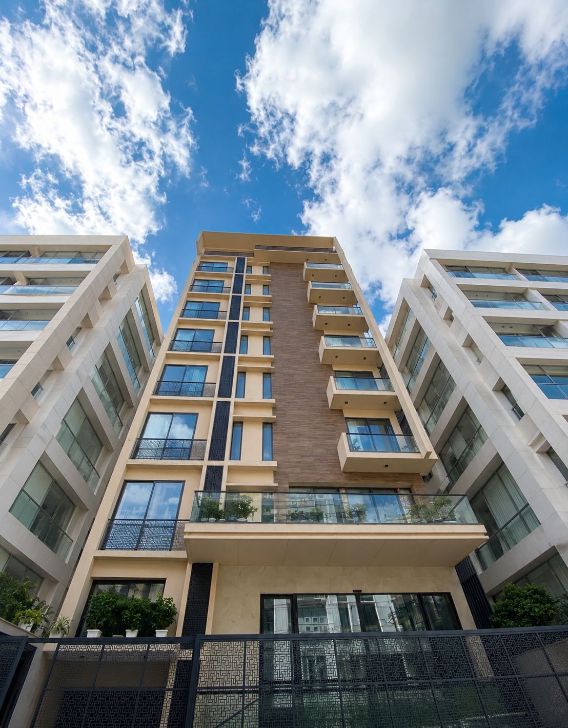 A high-rise building with multiple balconies and large windows, under a partly cloudy sky.