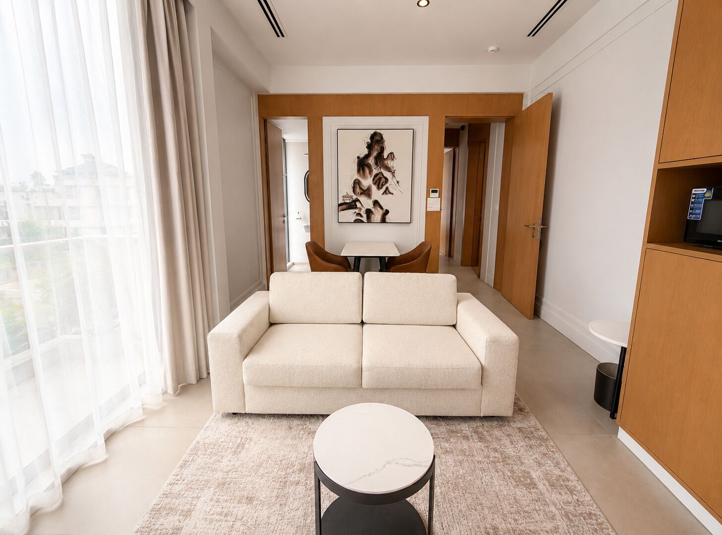 A modern living room with a sofa, a round coffee table, and a painting on the wall.