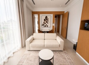 A modern living room with a sofa, a round coffee table, and a painting on the wall. - Barobi Apartment (Dhaka)