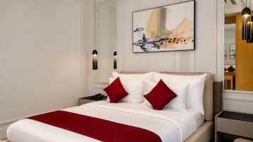 A modern hotel room with a large bed, a red throw blanket, and a painting above the bed.