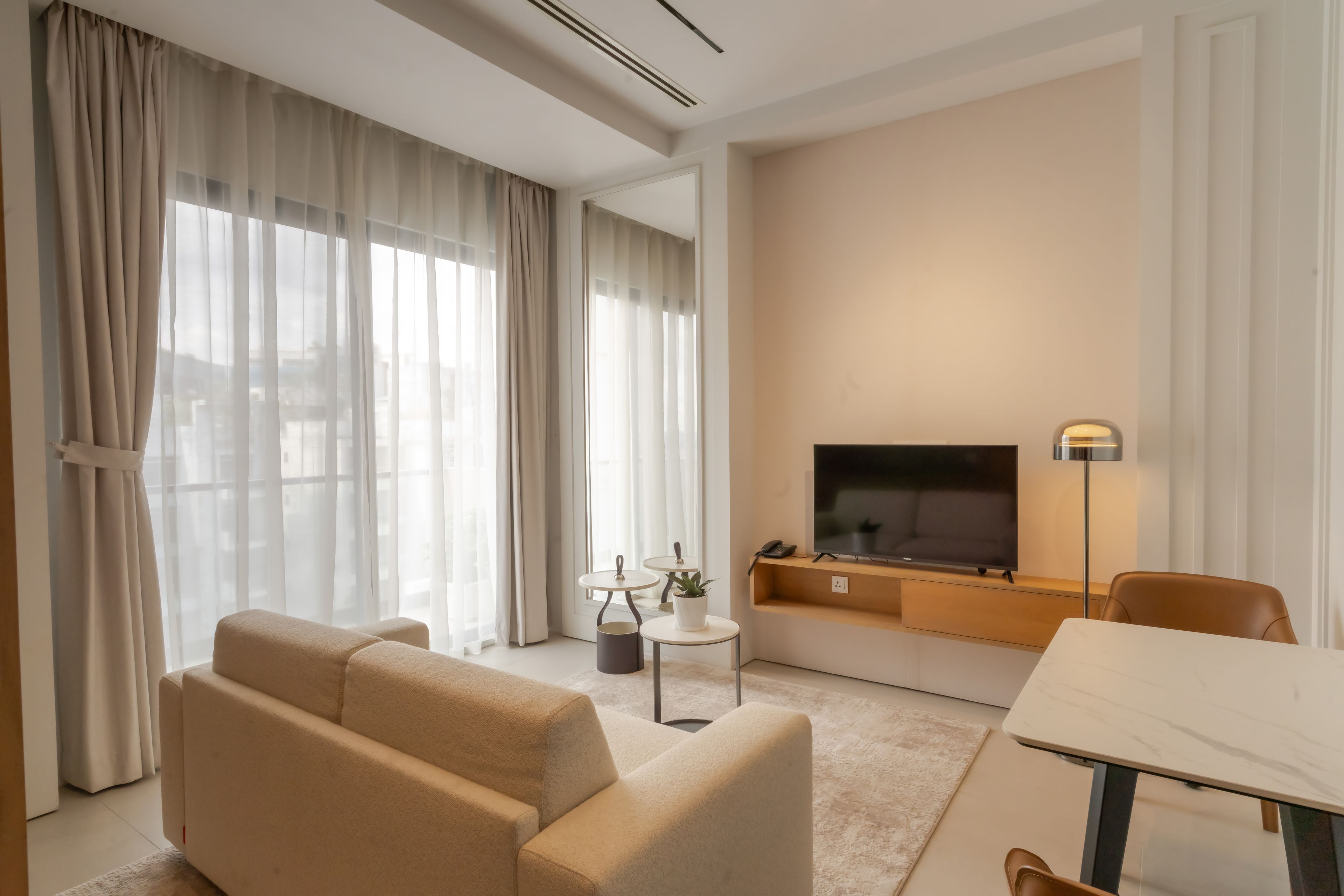 Un salon moderne avec un canapé, un téléviseur, une petite table et une lampe.