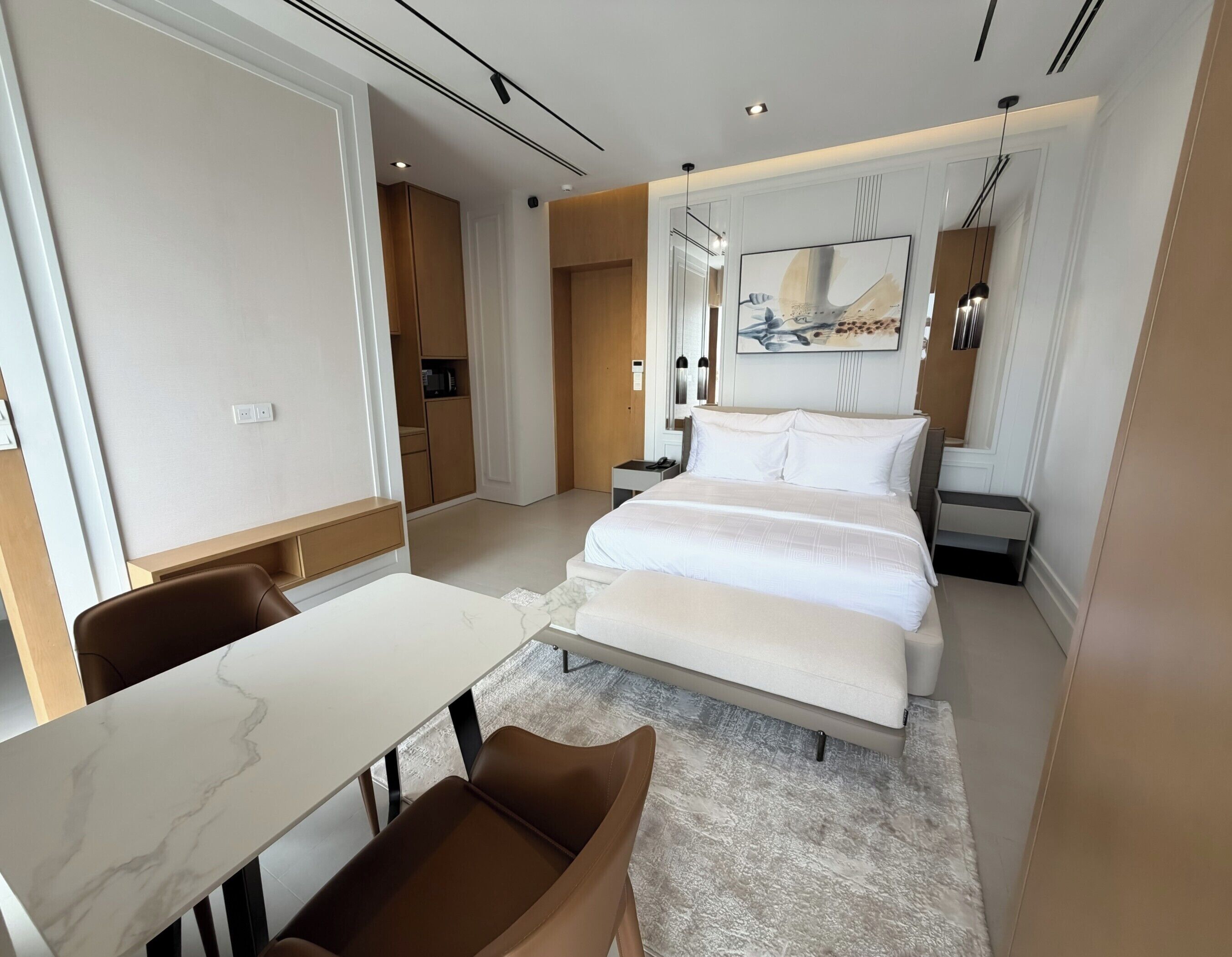 A modern hotel room with a large bed, a desk, and a chair.