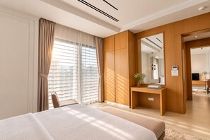 A modern hotel room with a large bed, a wooden desk, and a mirror.