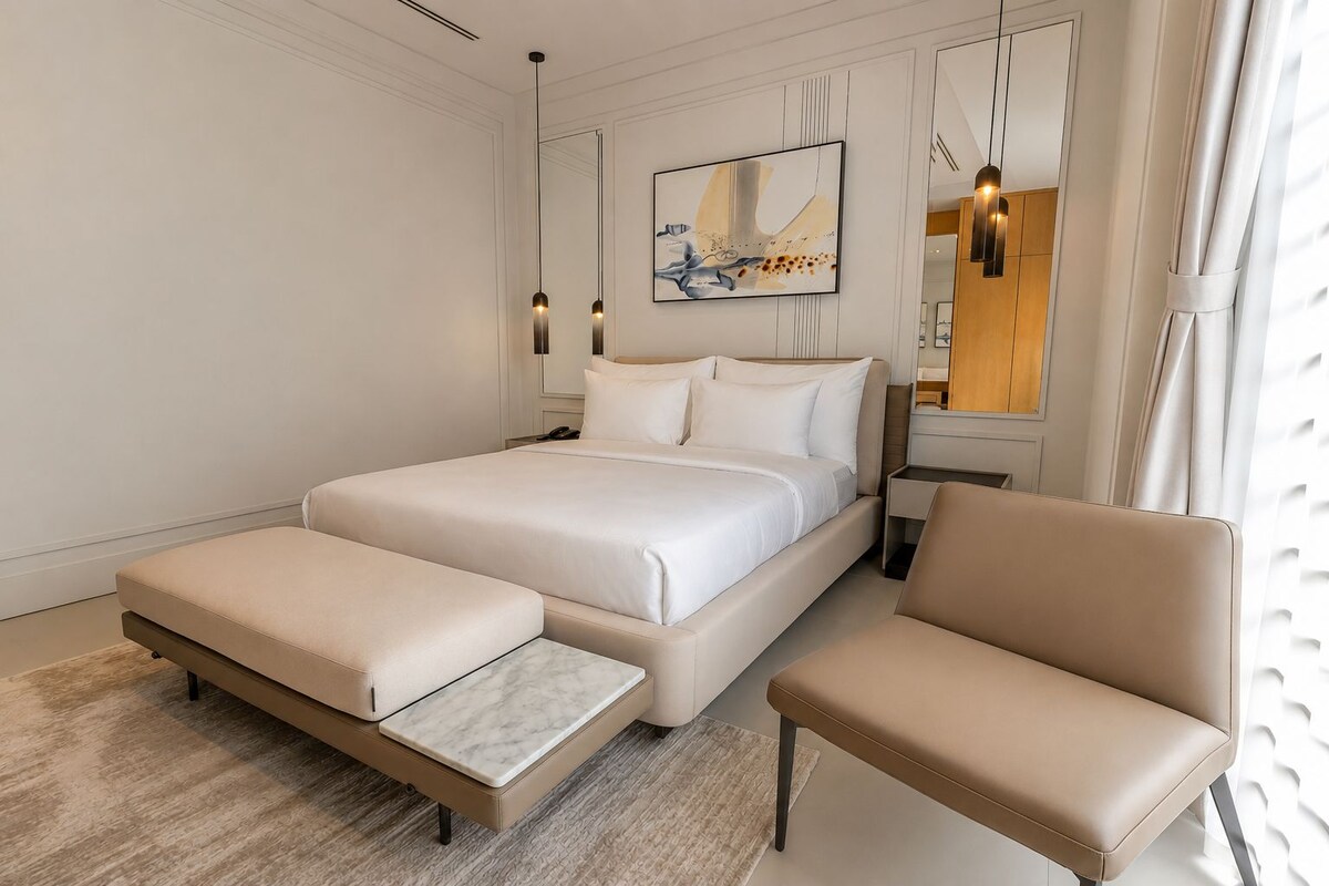 Un dormitorio moderno con una cama grande, una mesita de noche, una silla y un cuadro en la pared.