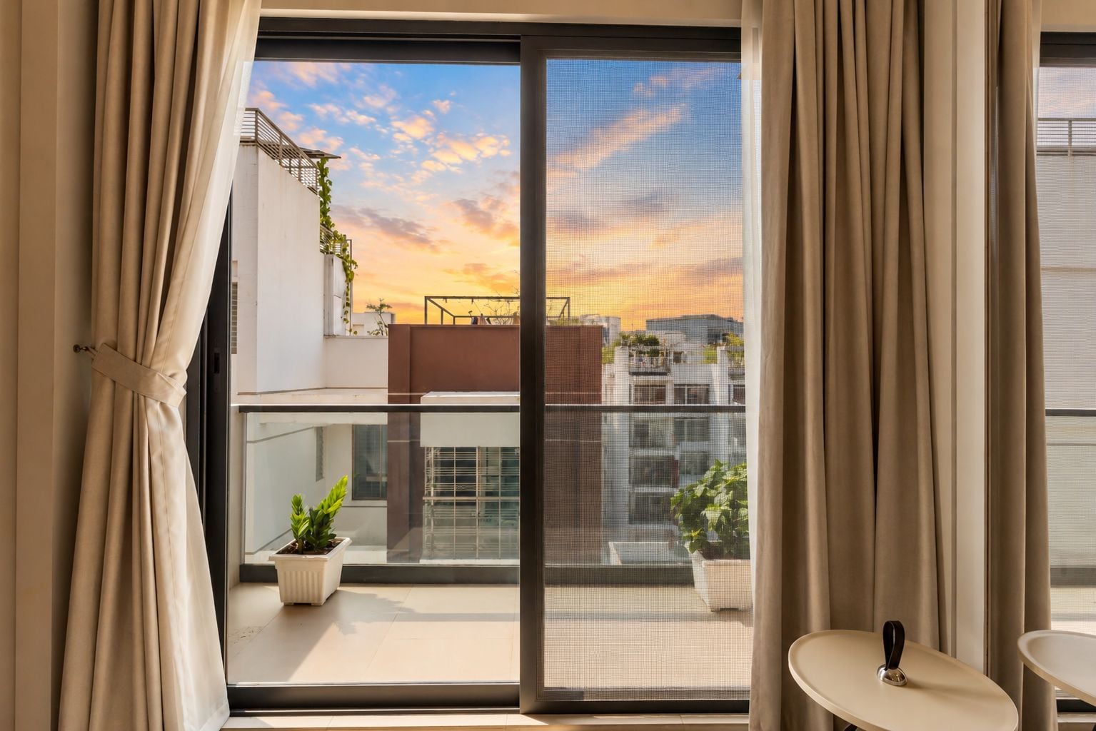 A balcony with a view of buildings and a sunset.