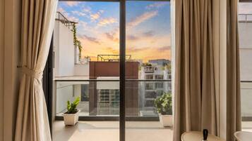 A balcony with a view of buildings and a sunset.