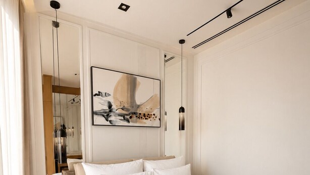 A modern bedroom with a large bed, bedside tables, a mirror, and a wall-mounted artwork.