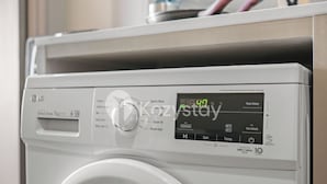 A front view of a white washing machine with a digital display and control panel. - Corvia by Kozystay - Kemayoran (Jakarta Pusat)