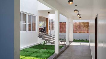 A modern interior with a staircase leading to a balcony, a small garden area, and a view of the outdoors.