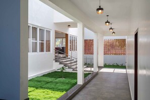 Un intérieur moderne avec un escalier menant à un balcon, un petit espace jardin et une vue sur l’extérieur.