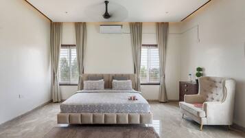 A bedroom with a large bed, a chair, an air conditioning unit, and a window with curtains.