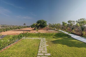 Un espace aménagé comprenant un chemin pavé, des pelouses et des arbres.