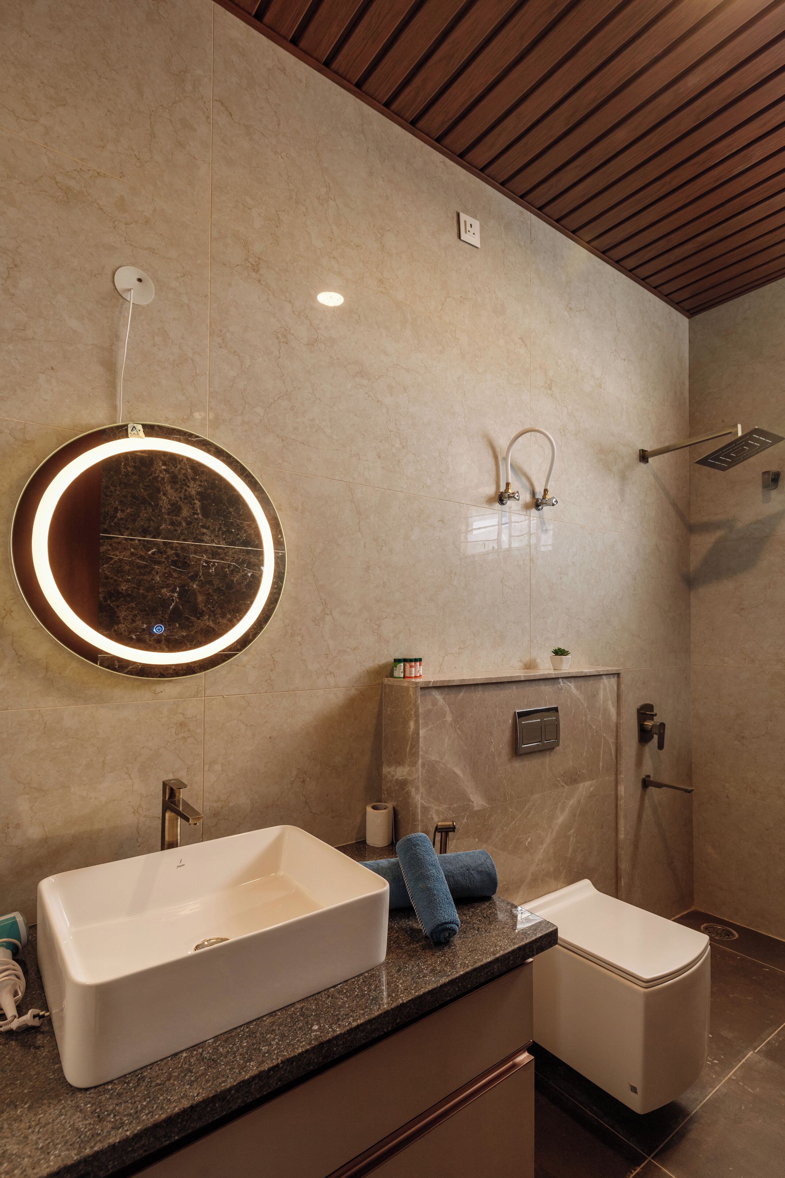 A modern bathroom with a large mirror, two sinks, a shower, and a toilet.