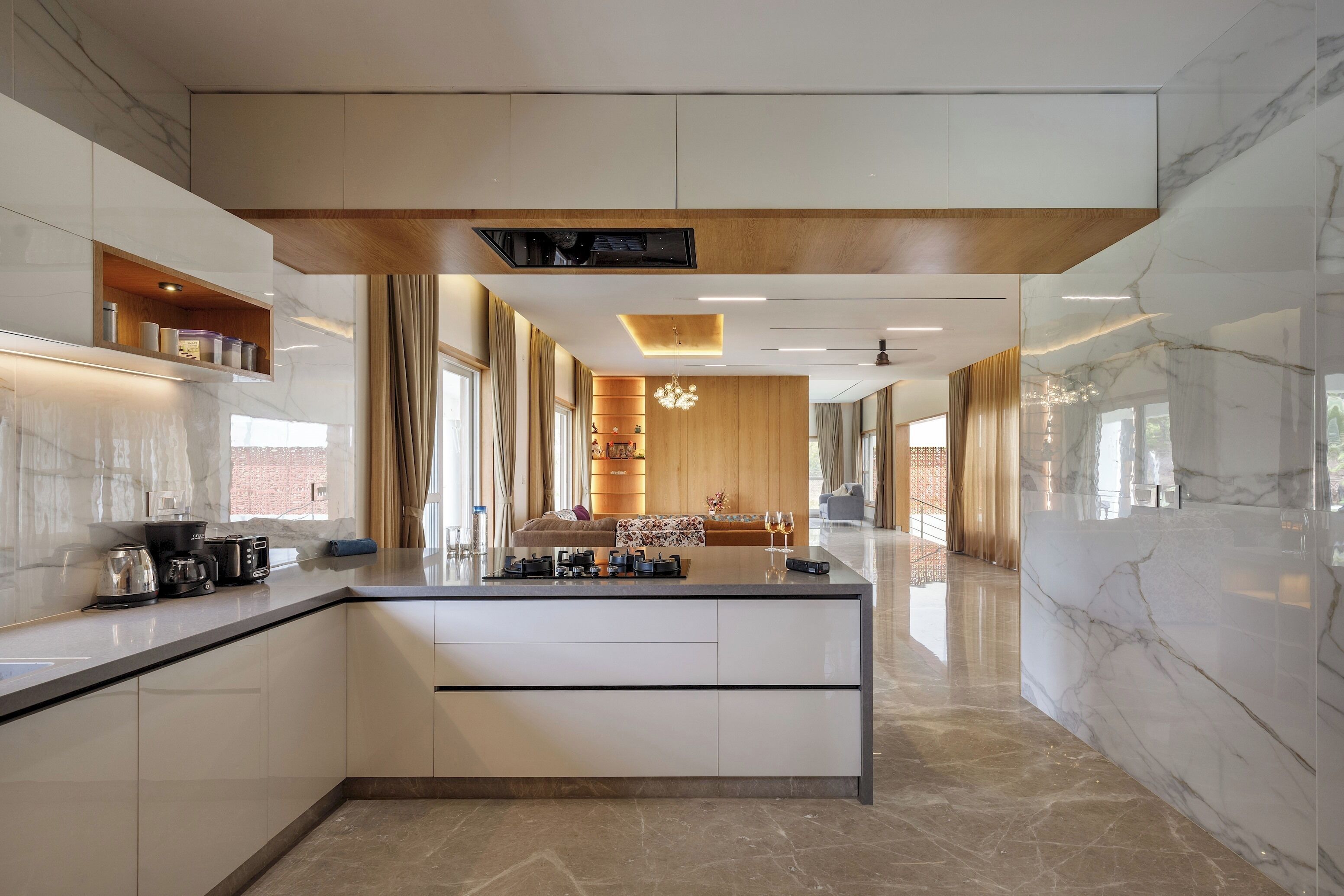 A modern kitchen with a central island, built-in appliances, and a wooden ceiling.
