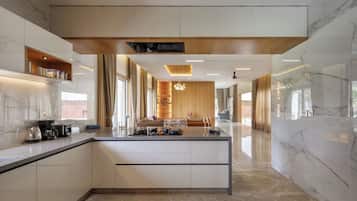 A modern kitchen with a central island, built-in appliances, and a wooden ceiling.