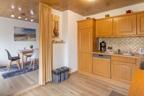 A modern kitchen with wooden cabinets, a coffee maker, and a dishwasher.