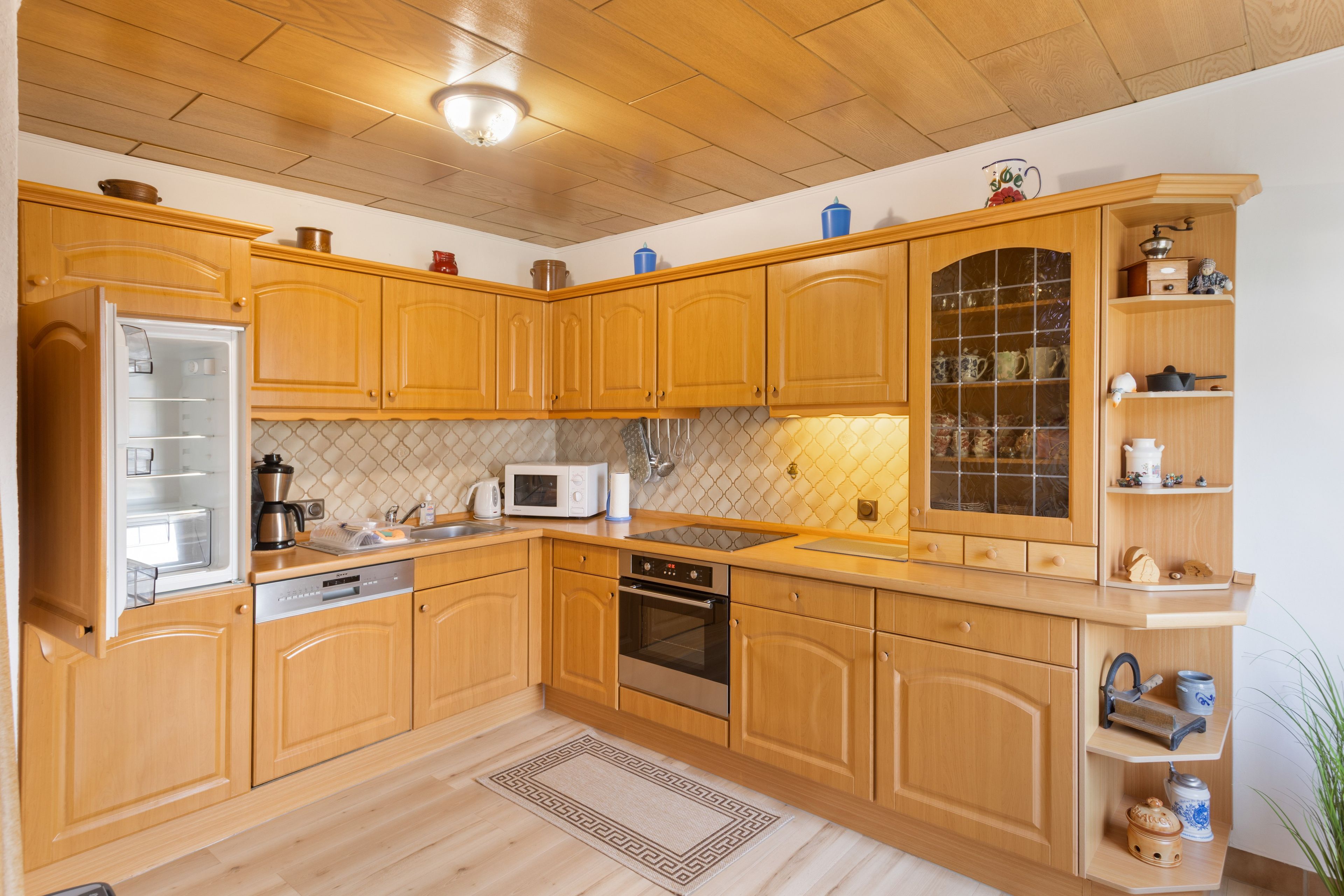 Una cucina con mobili in legno, un forno a microonde, un fornello e un frigorifero.