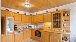 Een keuken met houten kastjes, een magnetron, een fornuis en een koelkast.