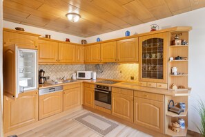 A kitchen with wooden cabinets, a microwave, a stove, and a refrigerator.