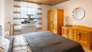 Een slaapkamer met een bed, een houten garderobe en een spiegel.