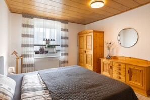 A bedroom with a bed, wooden wardrobe, and a mirror on the wall.