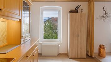 Et køkken med træskabe, et vindue med udsigt til grøn natur, og en radiator.